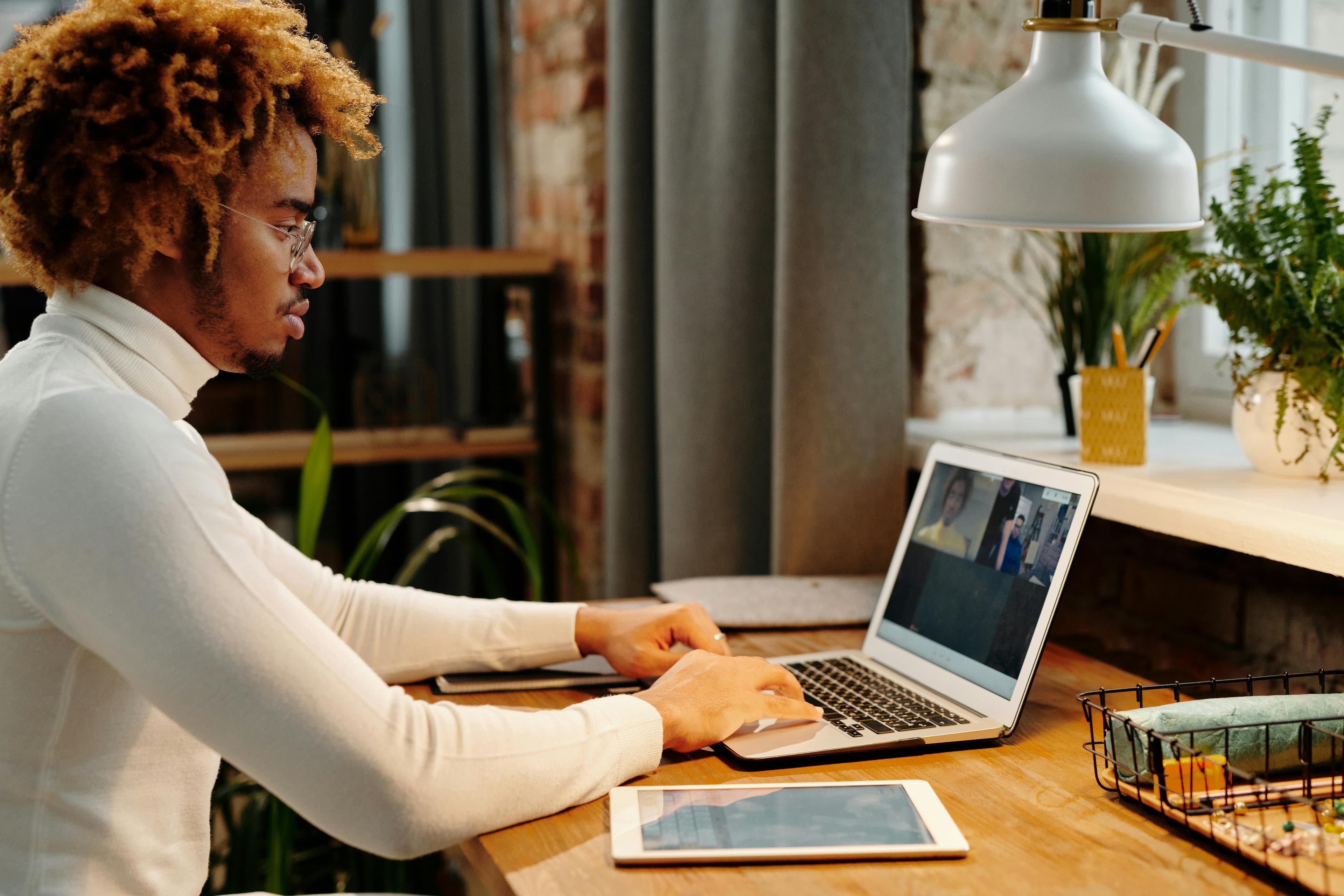 A person joining a video call on a laptop at a home desk
