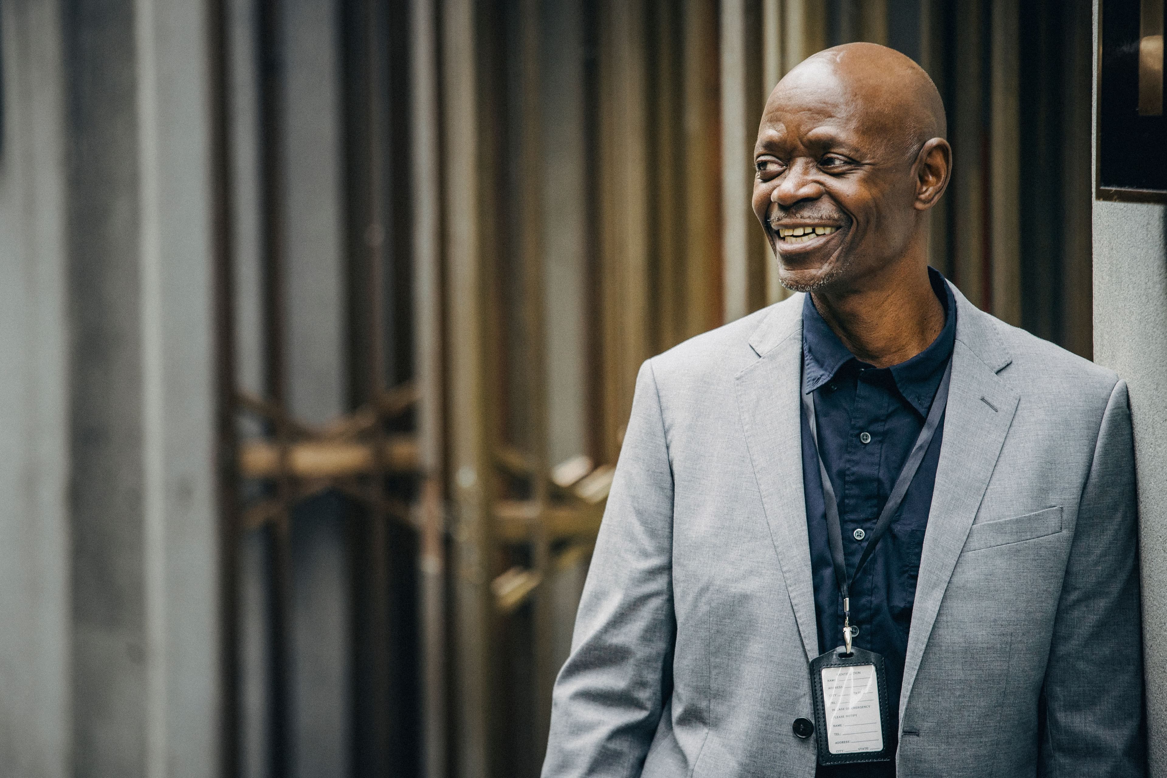 A man wearing a lanyard smiling as he walks through an office building