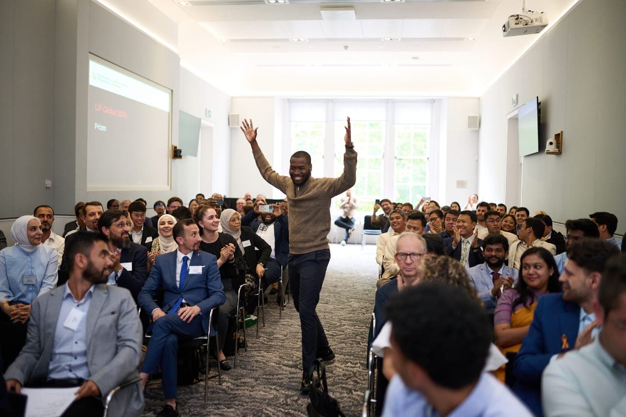 A founder celebrating a win with a room of supporters applauding